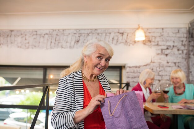 Fashionista. mulher sênior com sacolas de compras parecendo feliz