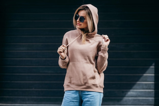 Fasion blonde Frau in braunen Oversize-Hoodie-Brille und Blue Jeans