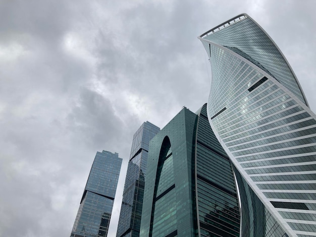 Fassade des modernen Wolkenkratzers mit Glaswänden Von unten des zeitgenössischen hohen Wolkenkratzers mit Glaswänden gegen bewölkten Himmel in der Innenstadt