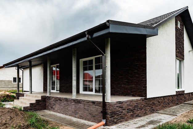 Fassade des neuen Hauses mit Zierputz und zerrissenen Ziegeln.