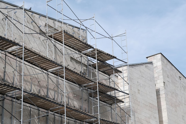 Fassadensanierung des Gebäudes gegen bewölkten Himmel Rekonstruktion der Gebäudehülle mit Gerüst