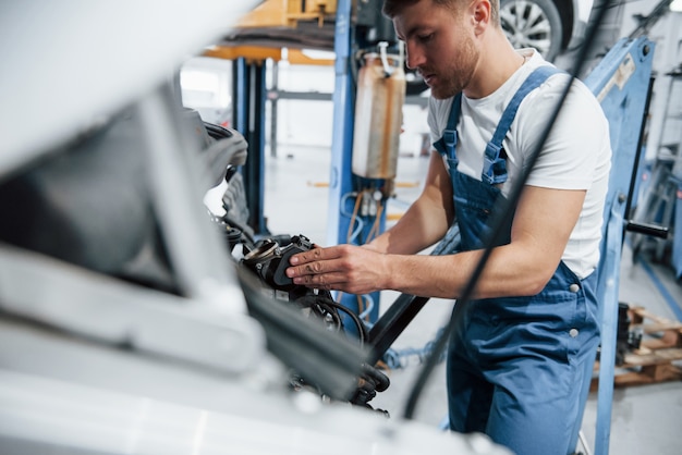 Fast fertig. Mitarbeiter in der blau gefärbten Uniform arbeitet im Autosalon