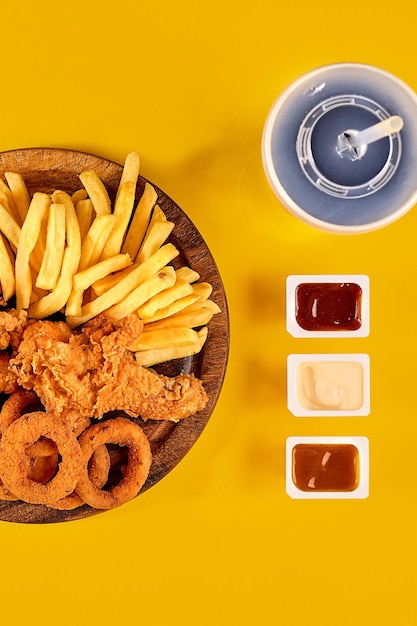 Fast-Food-Gericht auf gelbem Hintergrund Fast-Food-Set Brathähnchen und Pommes frites Fast Food zum Mitnehmen