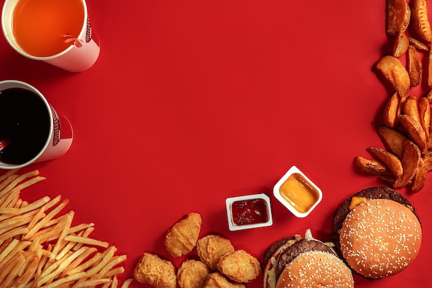 Fast-Food-Gericht Draufsicht Fleisch Burger Kartoffelchips und Glas Getränk auf rotem Hintergrund zum Mitnehmen Kompo...