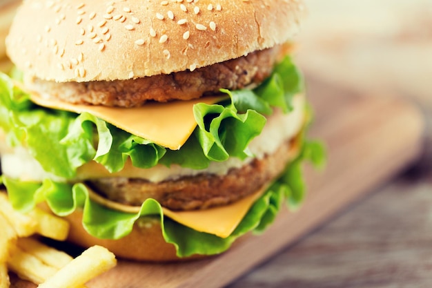 fast food, junk food e conceito de alimentação pouco saudável - close-up de hambúrguer ou cheeseburger na mesa