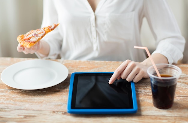fast food, pessoas, tecnologia e conceito de dieta - close-up de mãos de mulher com computador tablet pc, pizza e coca cola contando calorias na mesa
