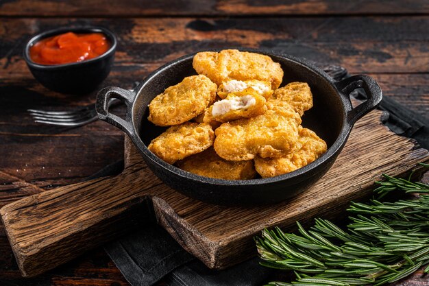 Fastfood - Nuggets fritos de pollo en una sartén. Fondo de madera. Vista superior.