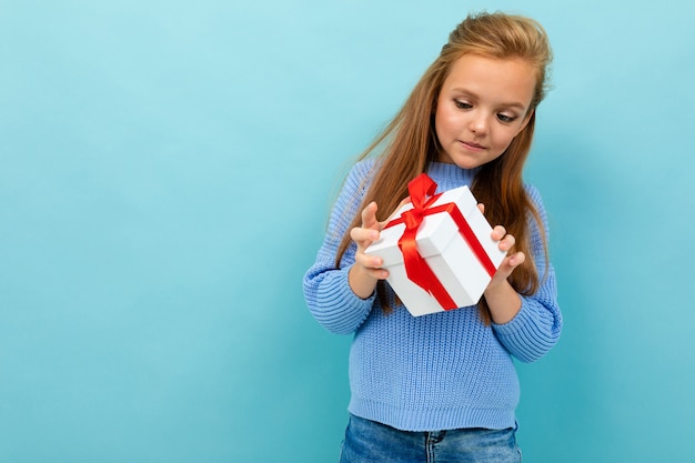 Fasziniertes schönes Jugendlichmädchen öffnet ein Geschenk