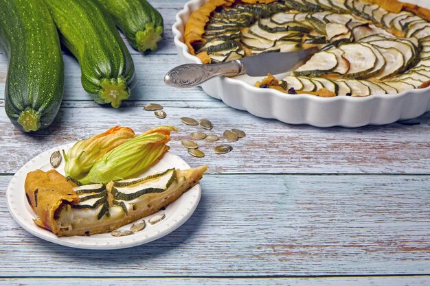 Fatia de abobrinha abobrinha e torta de queijo em um prato branco cercado por flores prato de torta de abobrinha