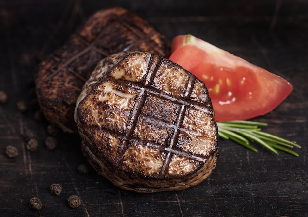 Fatia de bife grelhado de carne de porco suculenta na mesa de madeira com pimenta e erva de rosemarine