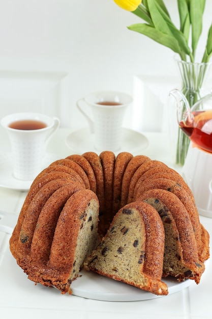 Fatia de bolo caseiro de banana Bundt na mesa branca servida com chá