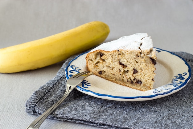 Fatia de bolo de banana caseiro ou pão no prato ornamentado com banana amarela orgânica