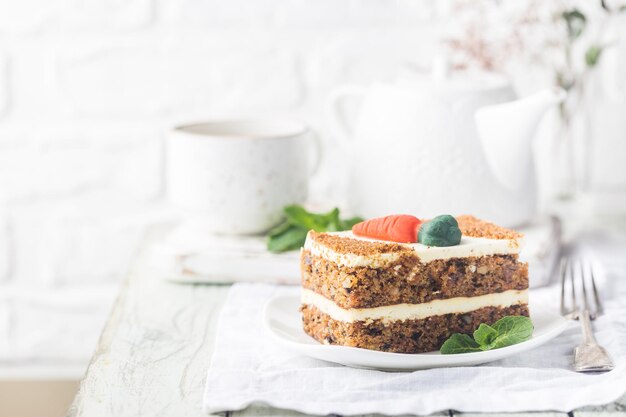 Fatia de bolo de cenoura com cobertura de cream cheese na mesa de madeira