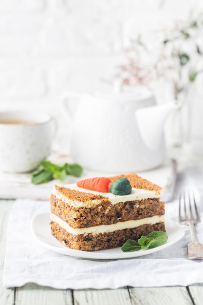 Fatia de bolo de cenoura com cobertura de cream cheese na mesa de madeira