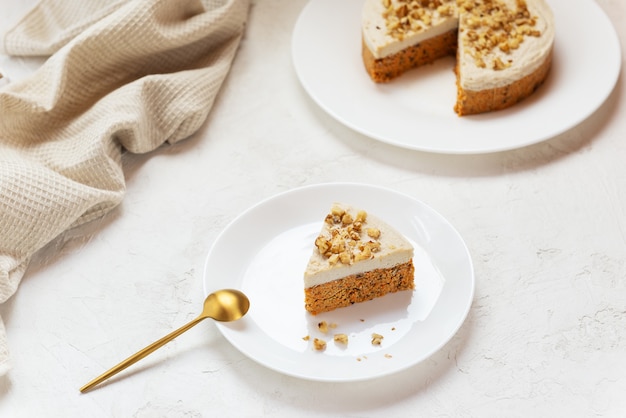 Fatia de bolo de cenoura com creme de coco e nozes em um prato branco bolo cru sem assados