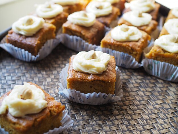 Fatia de bolo de cenoura com creme de queijo creme na bandeja de madeira