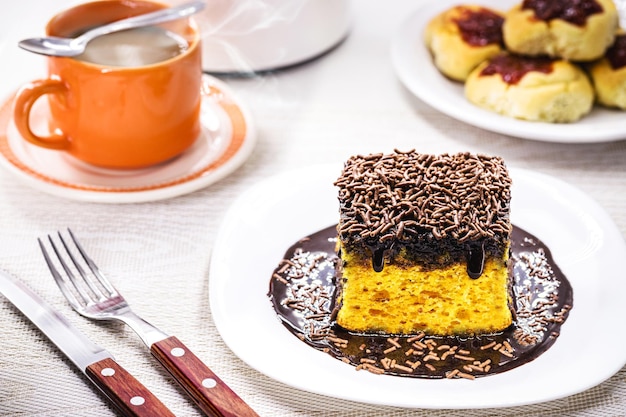 Fatia de bolo de cenoura com pingos de chocolate granulado com cobertura de bolo típico brasileiro feito em casa ou lanche da tarde de padarias
