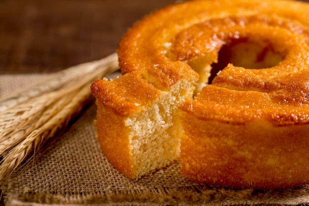 Fatia de bolo de farinha de trigo na madeira com galho de trigo ao lado.