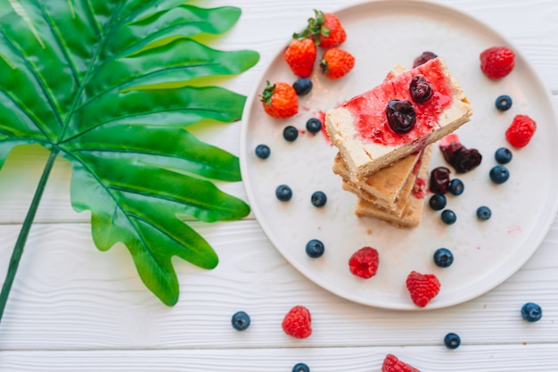 Fatia de bolo de queijo clássico com frutas frescas na chapa branca - sobremesa orgânica saudável do verão.