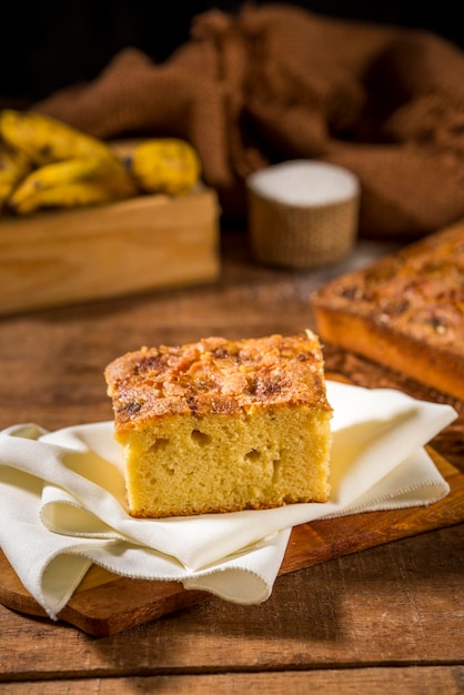 Fatia de bolo quadrado de banana em tecido rústico marrom em madeira