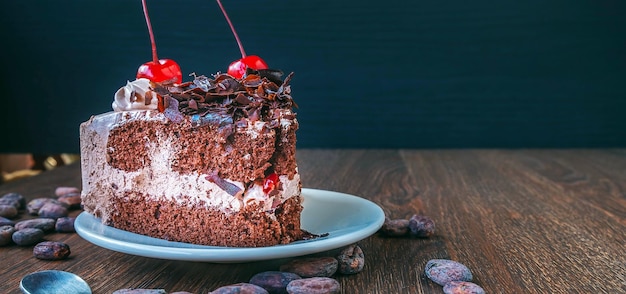 Fatia de cheesecake de chocolate no prato e grãos de cacau na mesa de madeira acima vista sobre um rústico