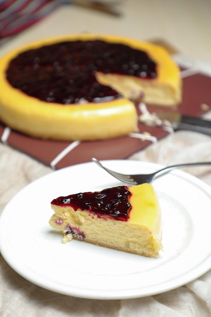 Fatia de cheesecake de mirtilo inclui caramelo com garfo e faca servido em prato isolado na vista superior da mesa do café assar alimentos