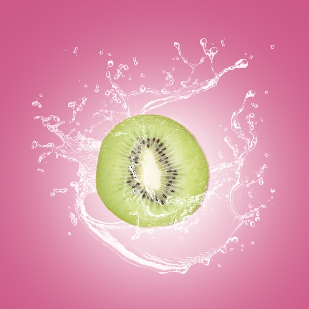Fatia de kiwi com respingos de água isolado no blackground rosa.