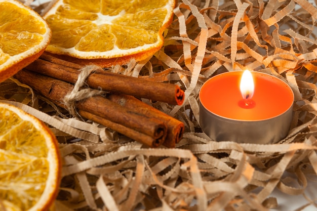 Fatia de laranja e paus de canela perfumados com uma vela acesa