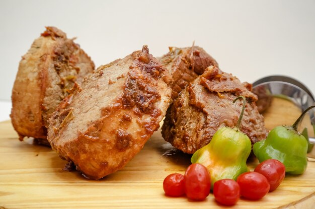 Foto fatia de panela de carne cozida na placa de madeira com faca e talheres