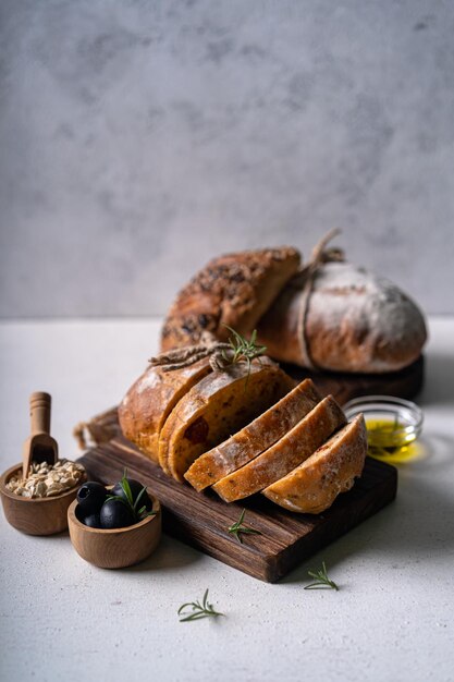 Fatia de pão ciabatta artesanal artesanal com azeitonas e alecrim em uma mesa abstrata branca