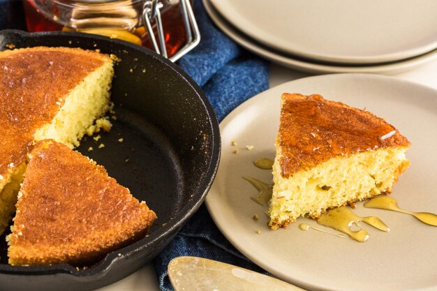 Fatia de pão de milho doce com mel no prato.