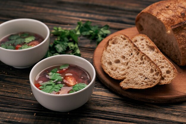 Fatia de pão e dois pratos de sopa em uma tábua de madeira