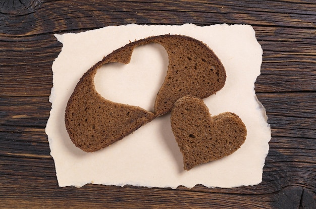 Fatia de pão preto com um corte em forma de coração em papel rasgado