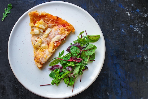 fatia de pizza e salada de folhas em um prato na mesa