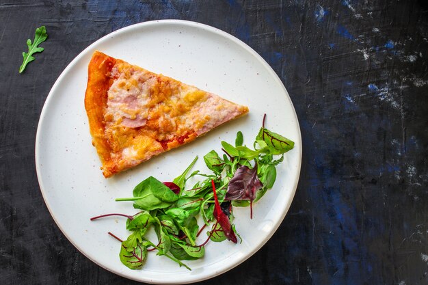 fatia de pizza e salada de folhas em um prato na mesa