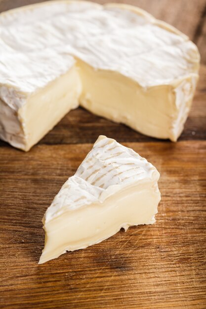 Foto fatia de queijo camembert na tábua de madeira