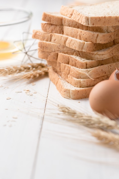 fatia pão com ingredientes para fazer pão com fundo de madeira