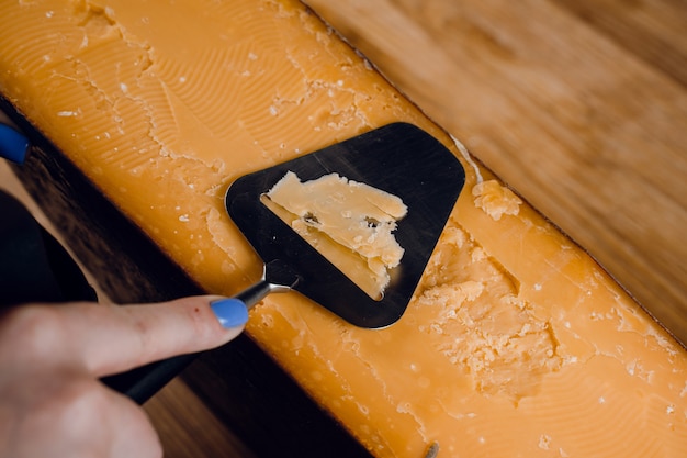 Fatiar queijo parmesão envelhecido com cristais usando uma faca de corte. Queijo duro com faca para aperitivo