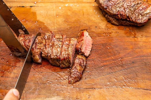 fatiar uma carne de picanha em uma tábua de madeira