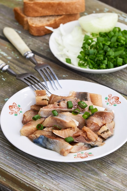 Fatias de arenque salgado com cebolinha em uma mesa de madeira