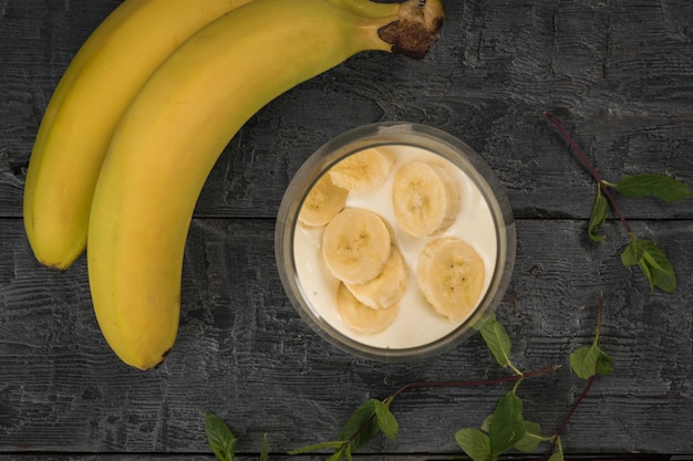 Fatias de banana em iogurte de banana em uma mesa de madeira
