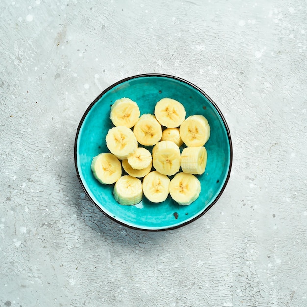 Fatias de bananas cruas frescas em um prato azul em uma mesa de pedra vista superior