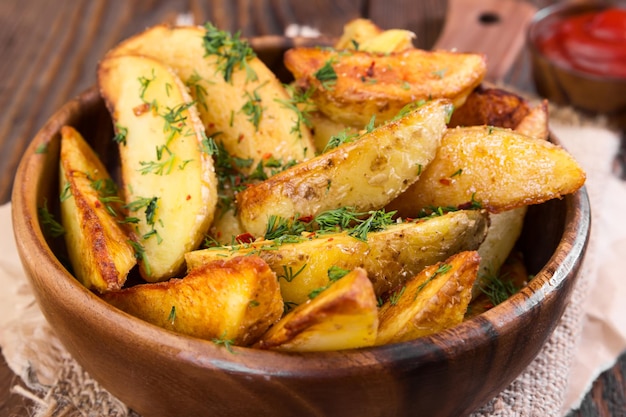 Fatias de batata com endro em tigela de madeira com fundo de madeira