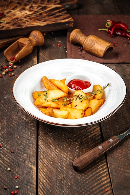 Fatias de batata decoradas com tomilho e ketchup na mesa decorada de madeira