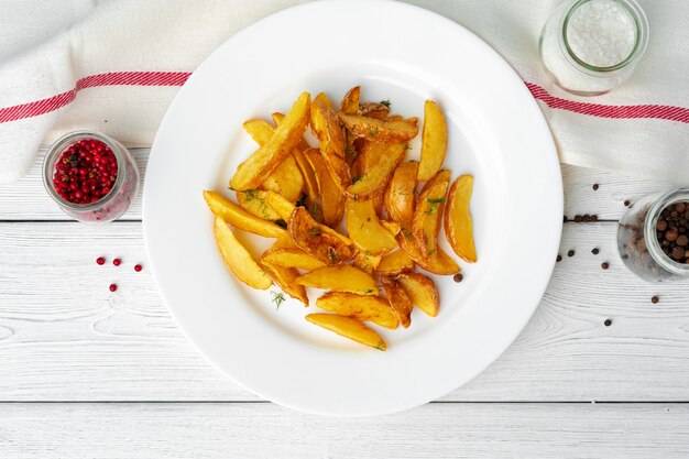 Fatias de batata frita no prato na mesa de madeira branca close-up