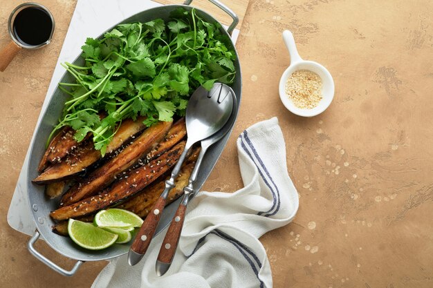 Fatias de berinjela grelhadas ou assadas em farinha de arroz com coentro e molho de soja no fundo da mesa rústica de concreto bege velho Vista superior com espaço de cópia