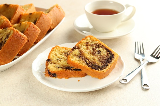 Fatias de bolo de mármore Bundt na chapa branca, servido com uma xícara de chá