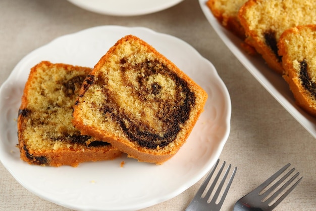 Fatias de bolo de mármore bundt na chapa branca, servido com uma xícara de chá