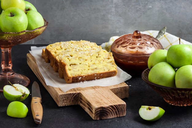 Fatias de bolo de nabo de coco e maçã em uma tábua de madeira em fundo escuro
