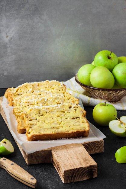 Fatias de bolo de nabo de coco e maçã em uma tábua de madeira em fundo escuro